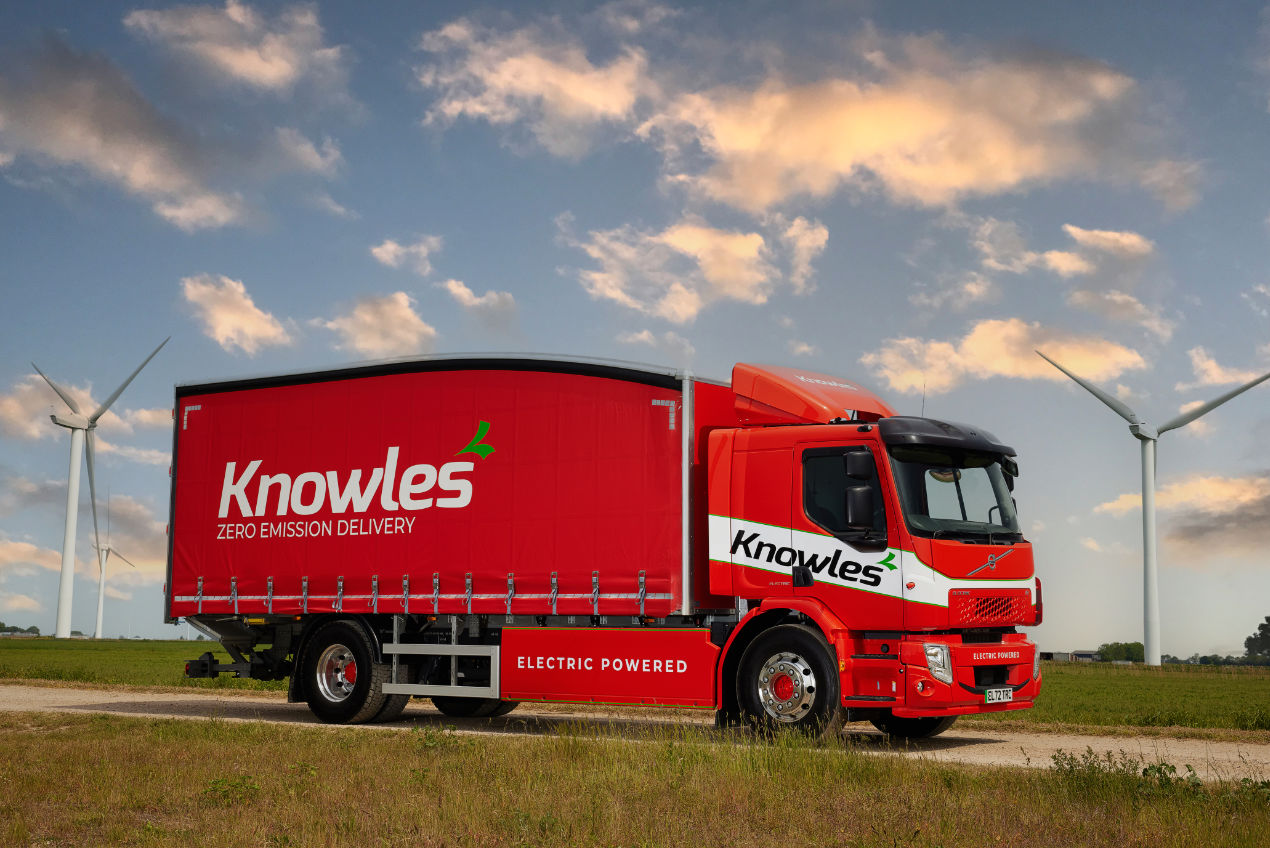 Knowles electric-powered lorry driving along surrounded by fields and wind turbines